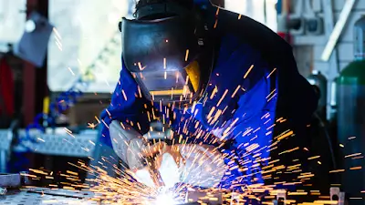 A welder in protective gear intensively focuses on a project.